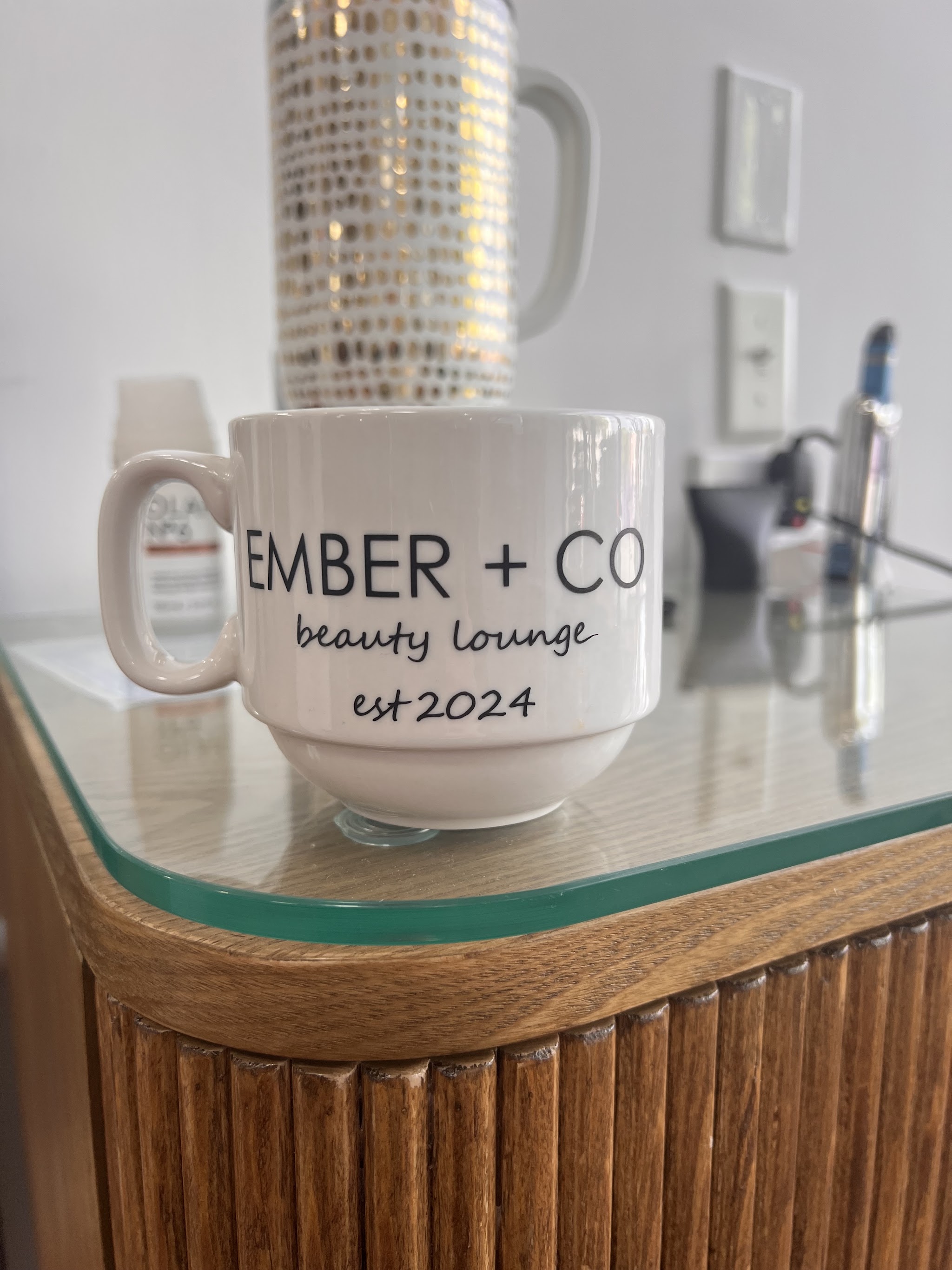 An EMBER + CO beauty lounge mug on a wooden station