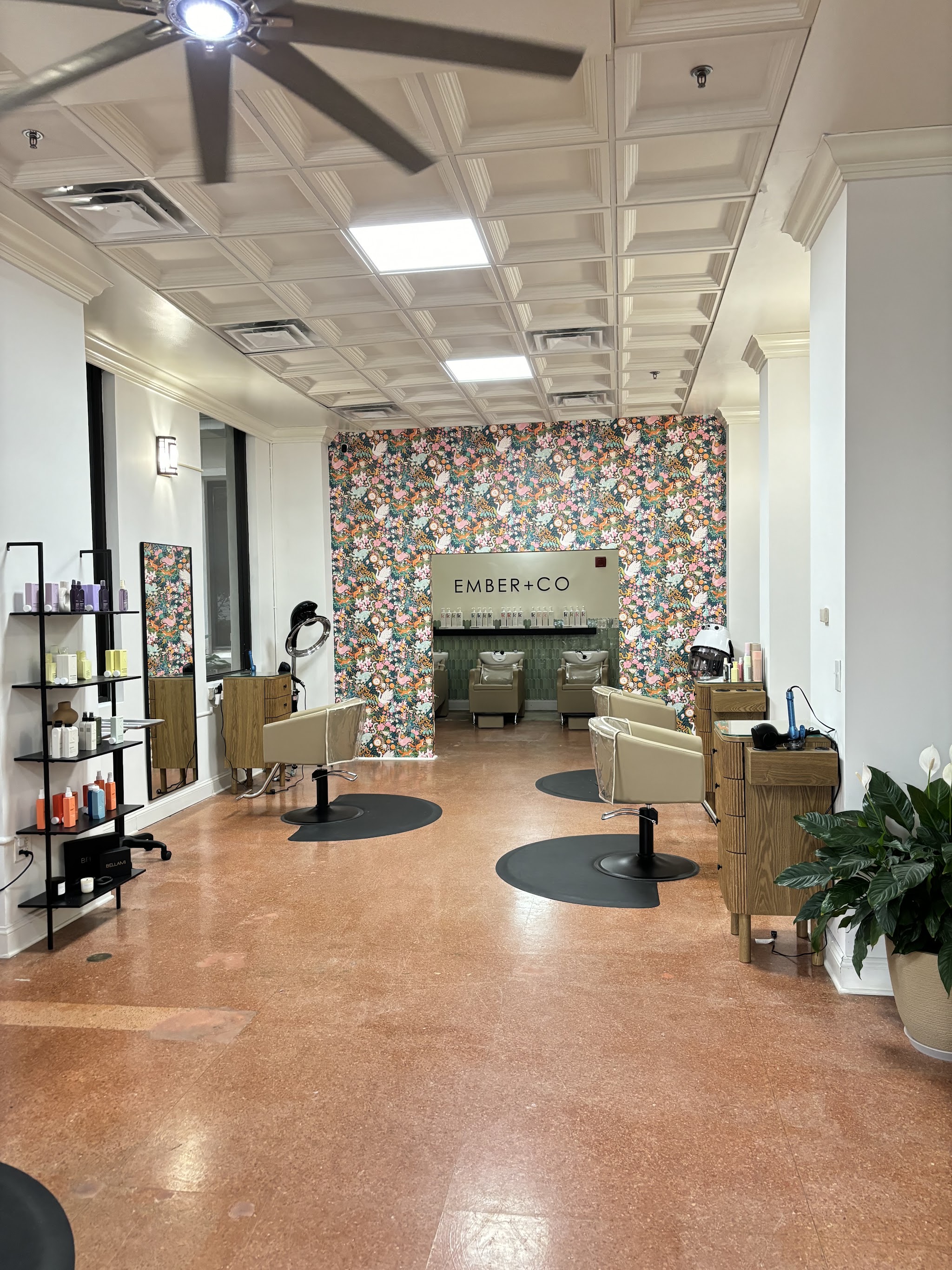 Inside the salon: styling chairs in front of a floral feature wall with the EMBER+CO sign