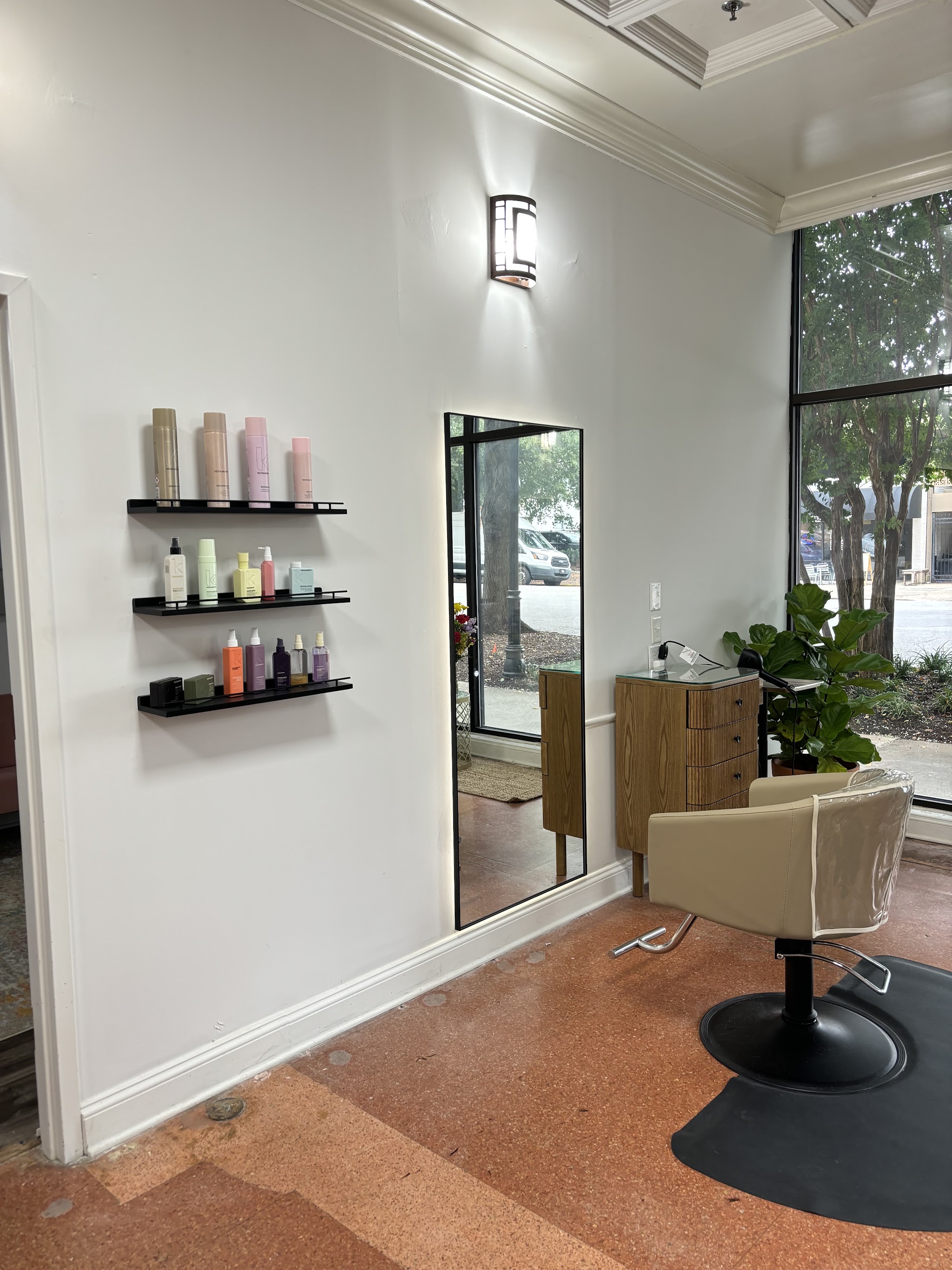 Wall shelves of hair products beside a mirror and a styling chair