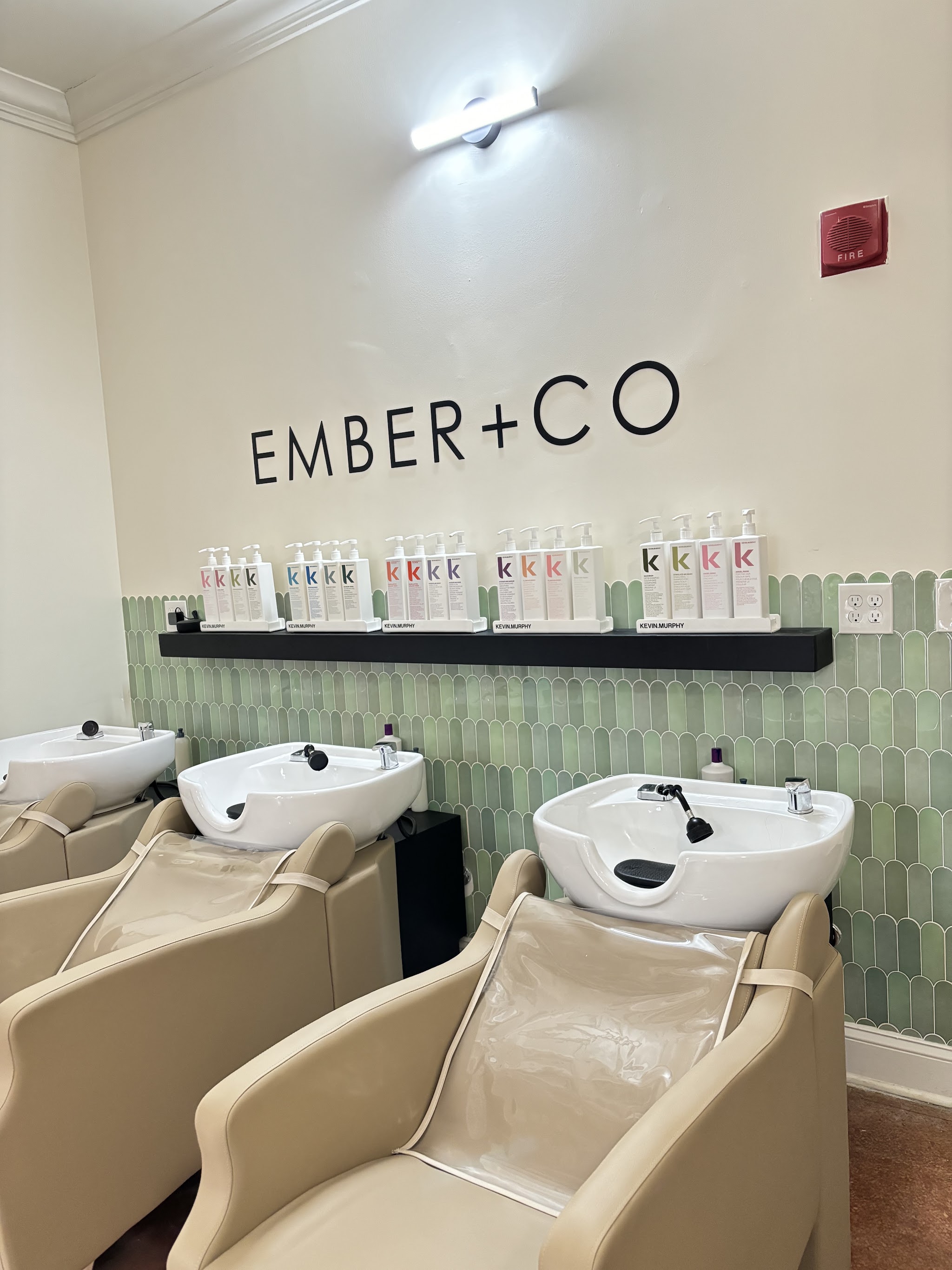 Our shampoo basins in front of green tile and the EMBER+CO sign